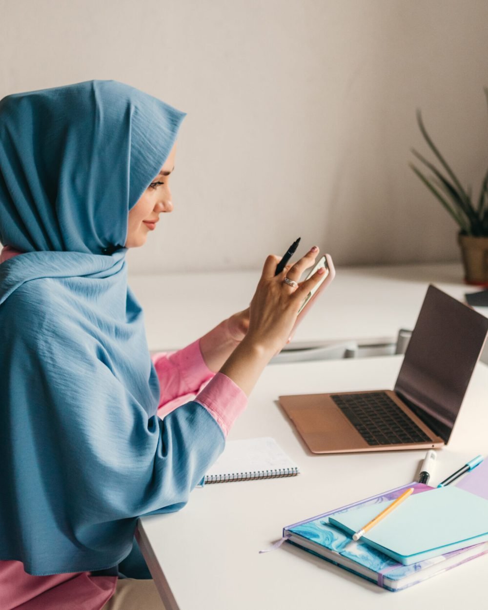 young pretty modern muslim woman in hijab working on laptop in office room, education online, remote work freelancer, using smatphone thinking